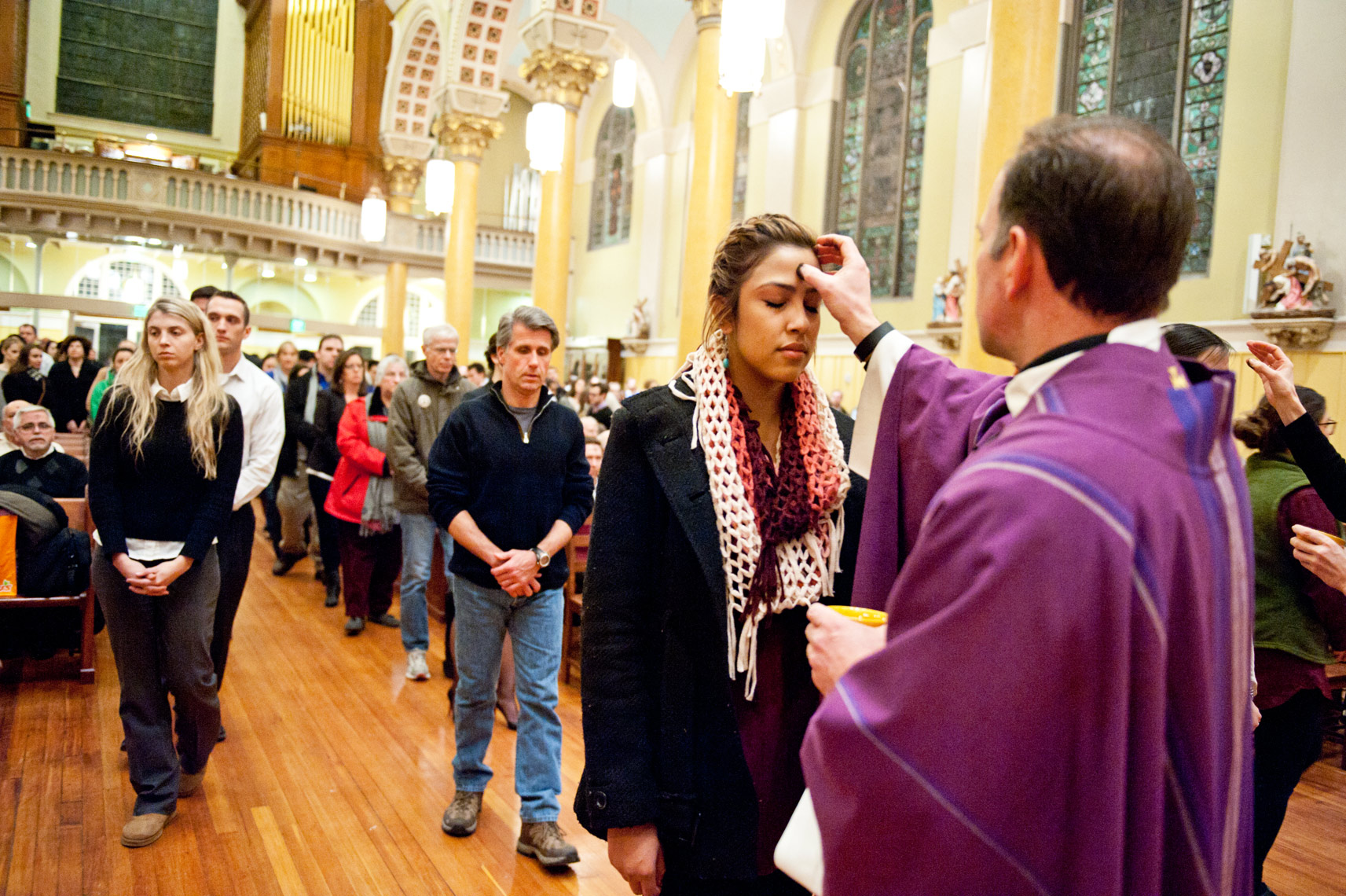 the Reverend John Unni placing repentance ashes on foreheads of parishioners St. Cecilia Parish Ash Wednesday